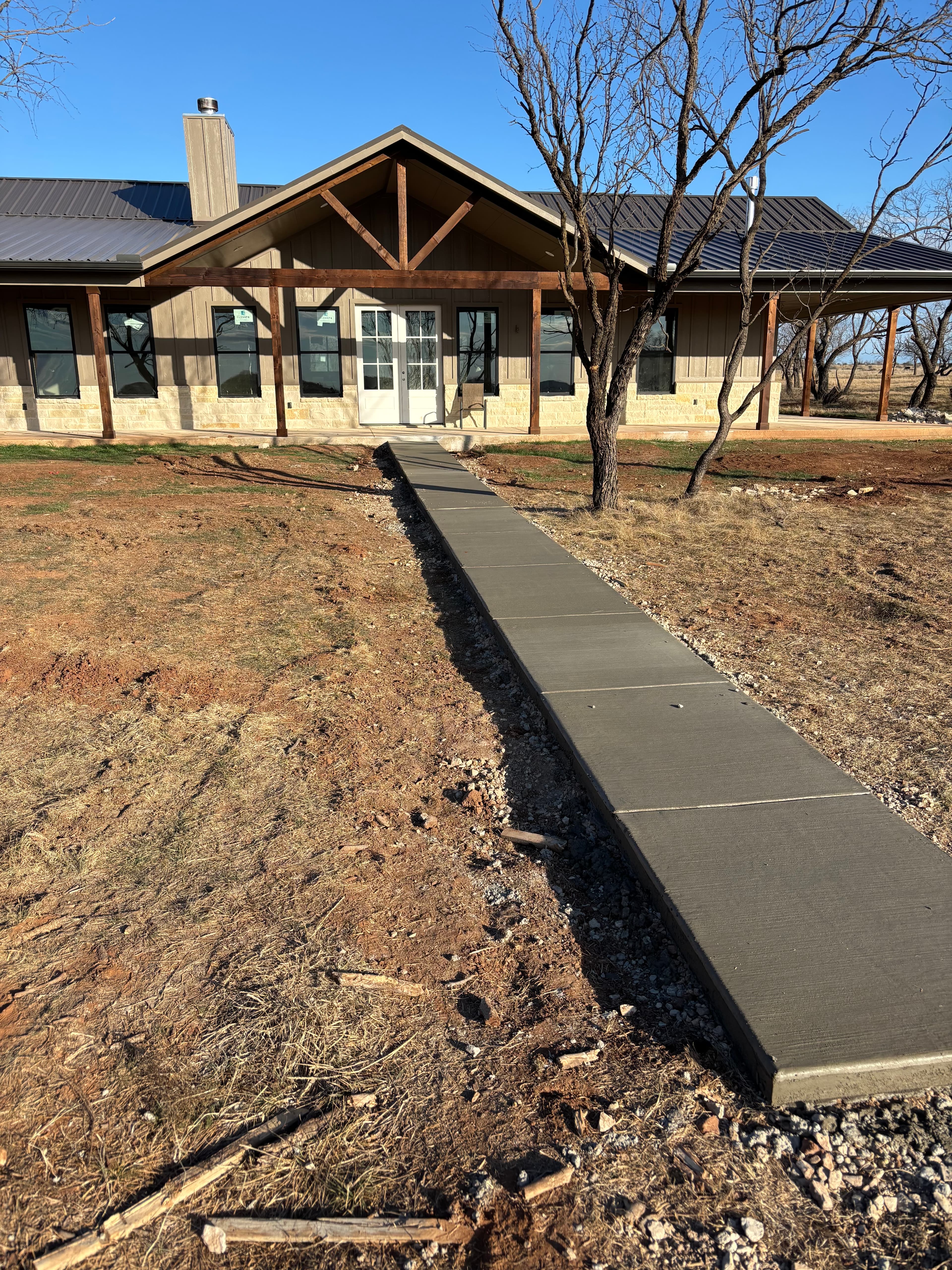 Finished concrete sidewalk flatwork alongside a residential structure in North Texas