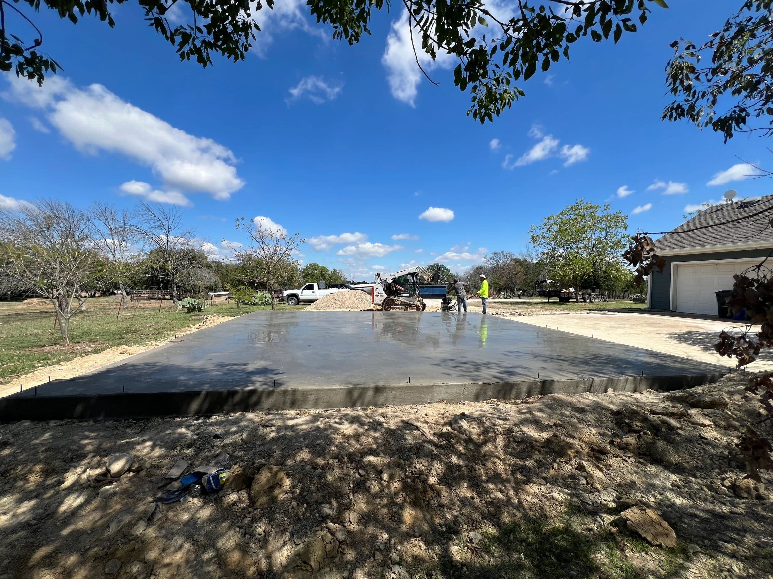 Concrete flatwork pad with skid steer on rural North Texas property
