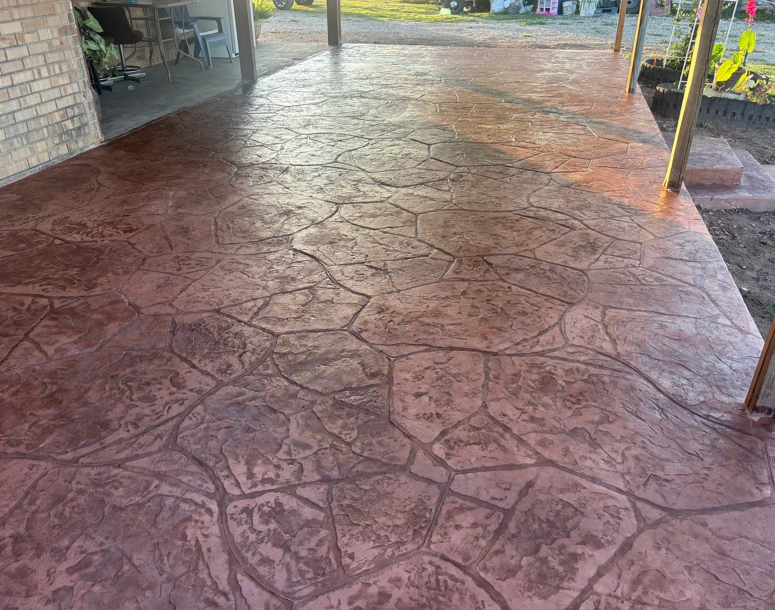 Freshly sealed stamped concrete patio with a flagstone pattern under a covered porch in Stephenville, Texas